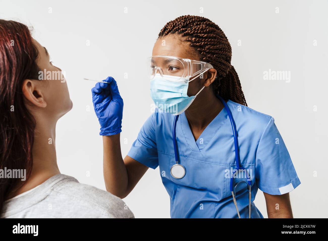 Black doctor wearing face mask making covid test to white woman ...