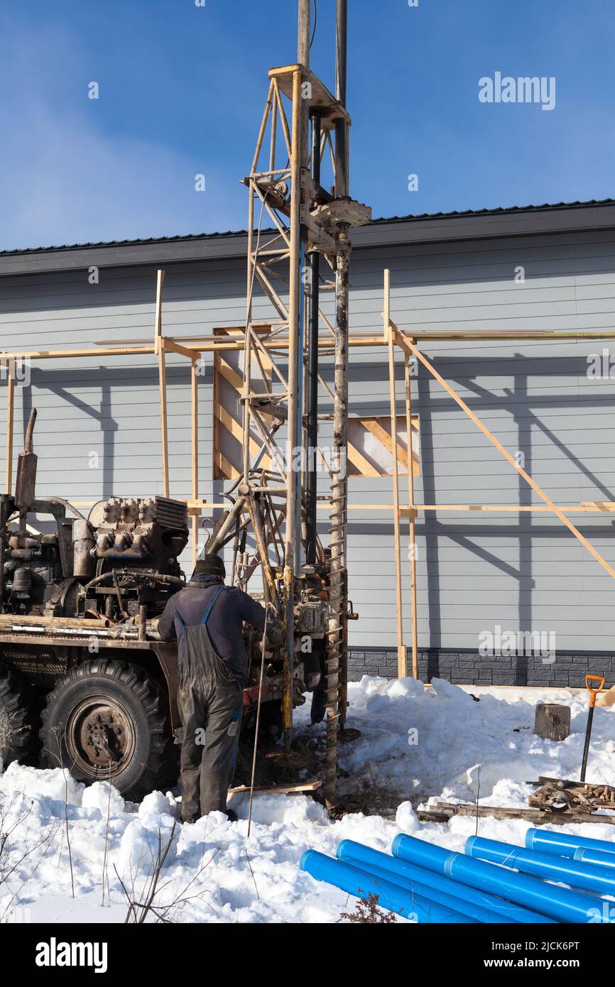 Making artesian well in the land when the ground water hole drilling machine installed for the water supply, winter Stock Photo