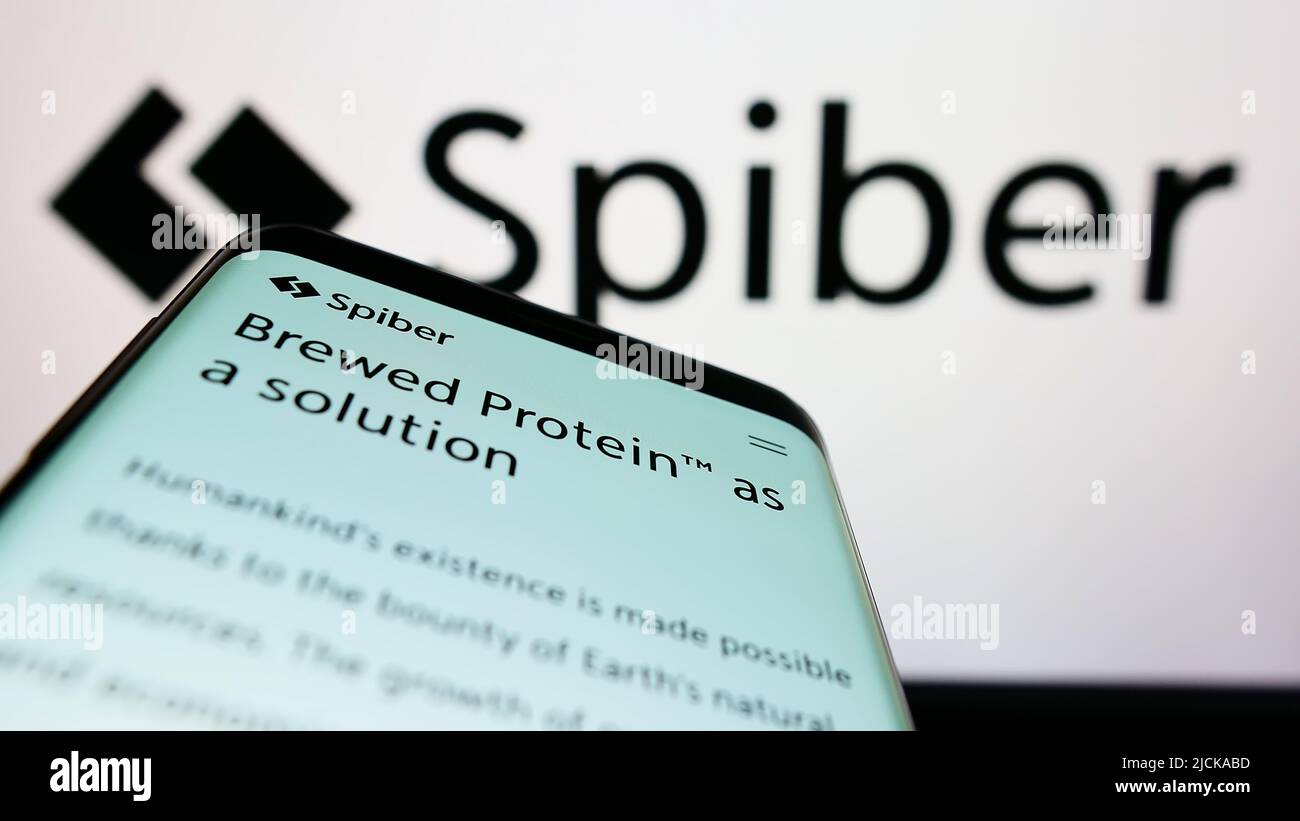 Mobile phone with website of Japanese biotechnology company Spiber Inc. on screen in front of business logo. Focus on top-left of phone display. Stock Photo