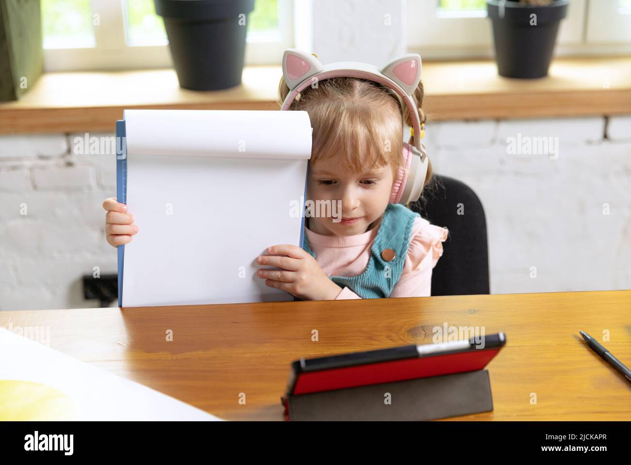 Live portrait of cute little girl, preschool age kid leaning at home ...