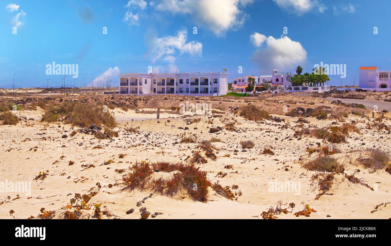 Beautiful beach coast landscape, sand dunes, colorful seaside vacation homes cottages and hotel building, blue summer sky - El Cotillo, Fuerteventura Stock Photo