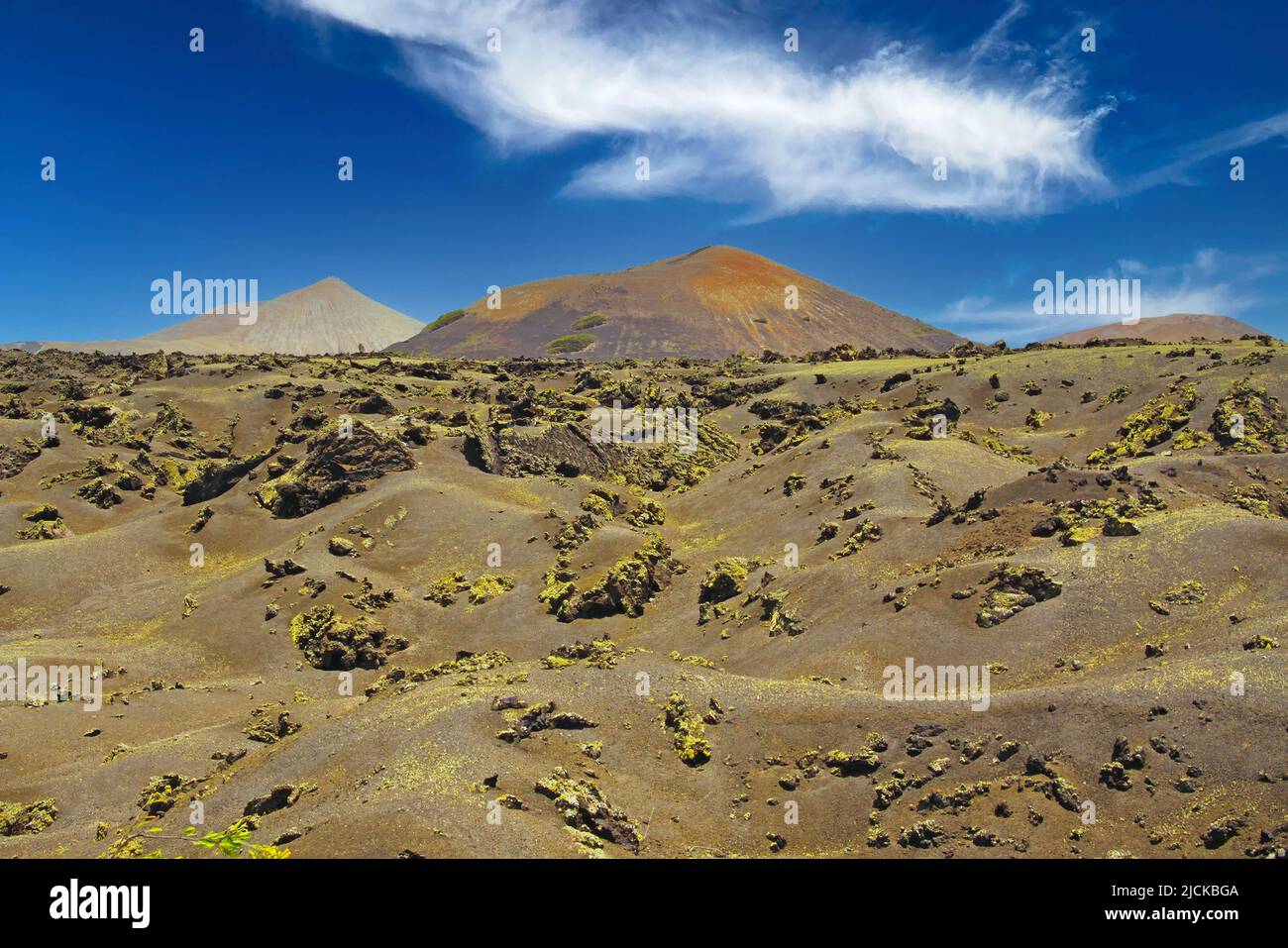 Beautiful barren dry landscape,  black jagged lava sand field, red volcano  cone, clear blue summer sky - Timanfaya NP, Lanzarote Stock Photo