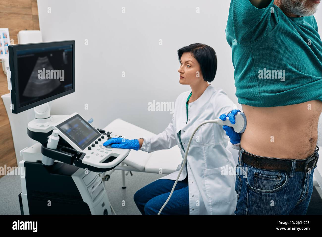Male patient getting kidneys sonography exam standing near ultrasound specialist and ultrasound machine at hospital. Ultrasound of kidneys Stock Photo