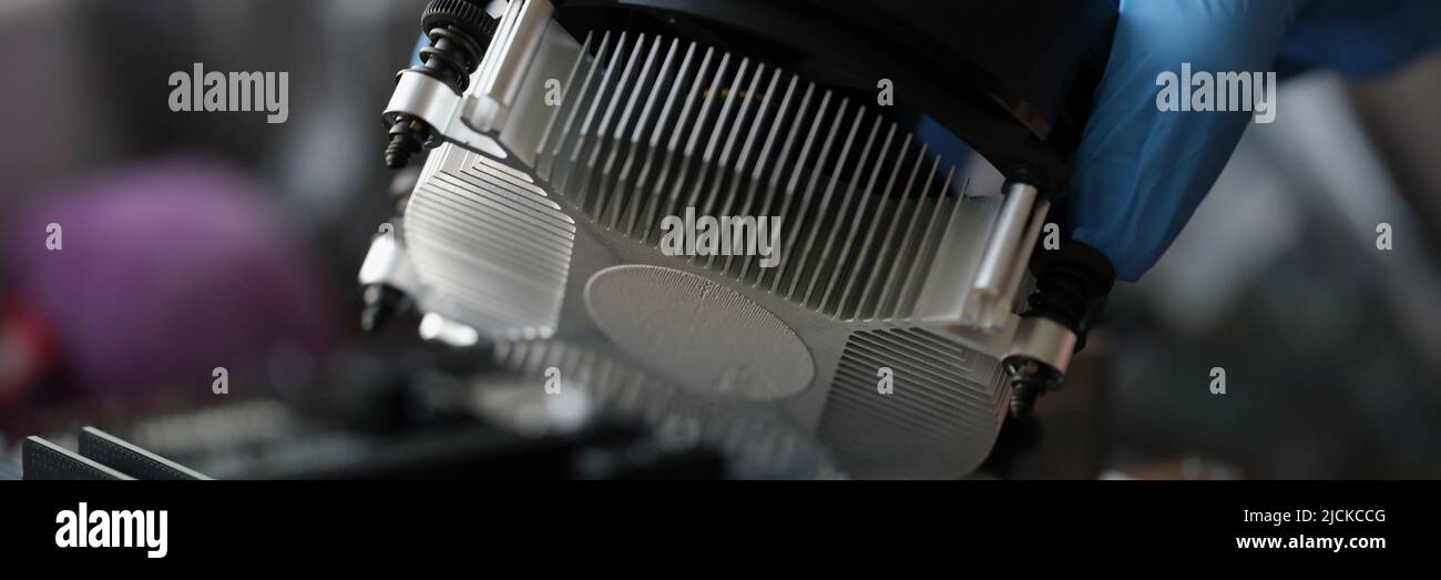 Person installing black cooler fan with copper tubes on computer processor Stock Photo