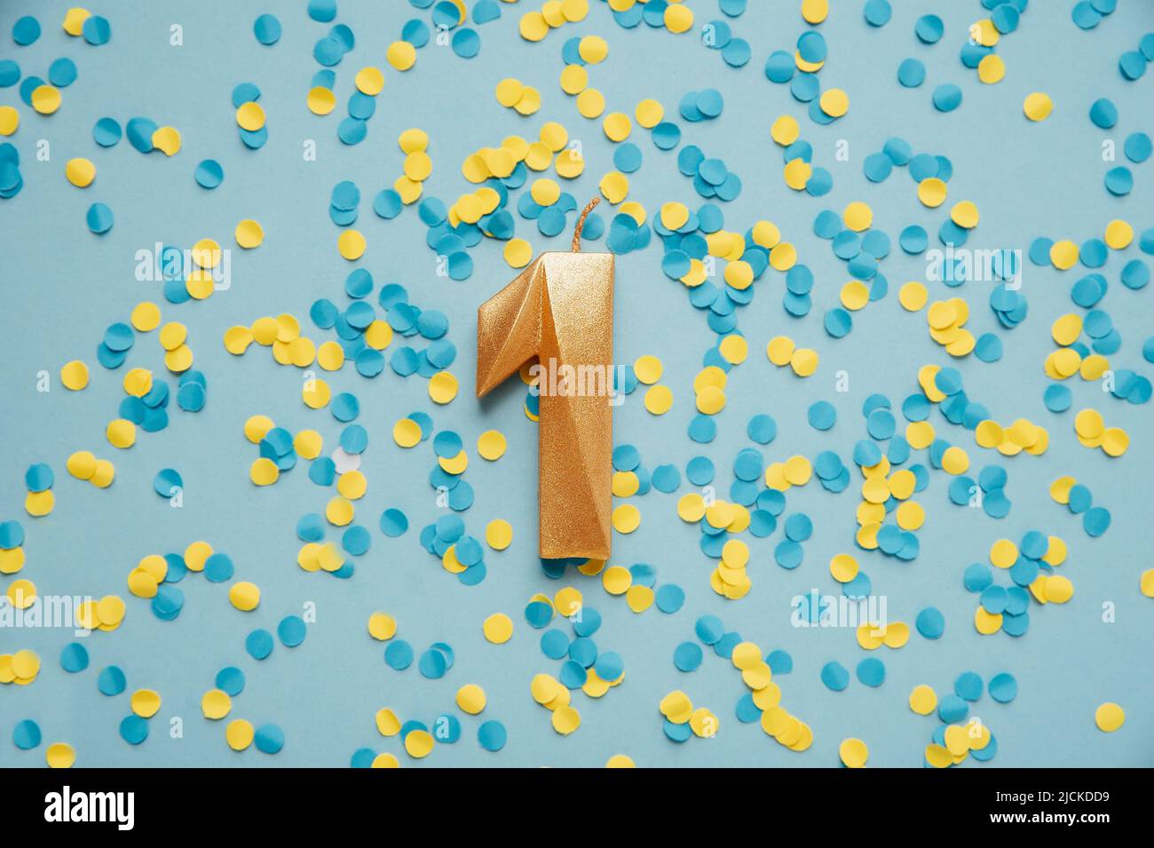 Number 1 one golden celebration birthday candle on yellow and blue confetti Background. One year birthday. concept of celebrating birthday, anniversary, important date, holiday Stock Photo