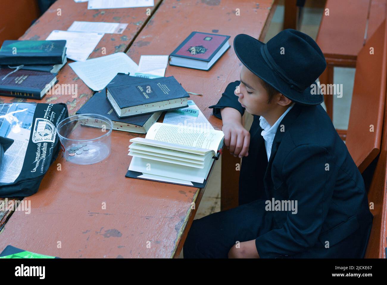 A teenage Hasidic boy studies the writings of the Lubavitcher Rebbe in the main Chabad synagogue in Crown Heights, Brooklyn, New York City. Stock Photo