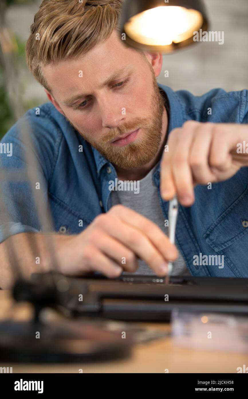 young male engineer repairs a laptop Stock Photo