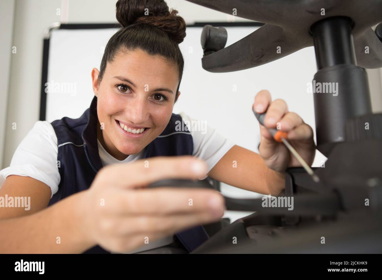 female worker adjusting an office chair with a screwdriver Stock Photo ...