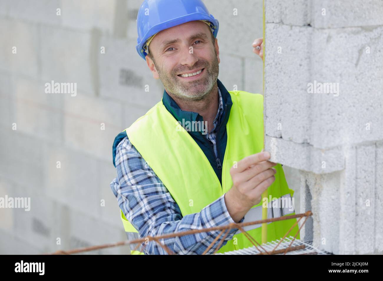 a mason measuring concrete block Stock Photo Alamy