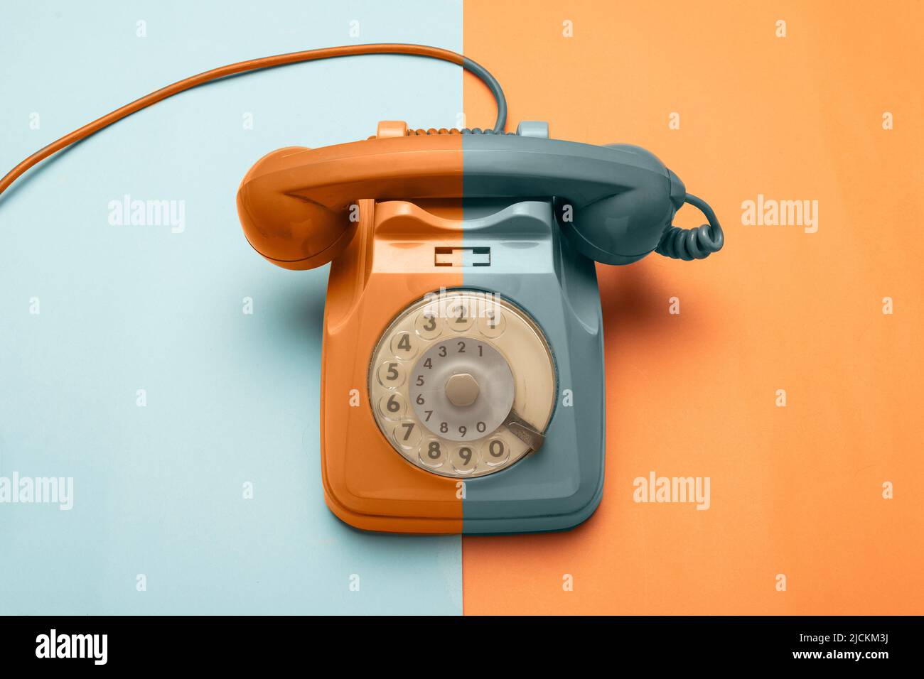 Teal and orange retro disk telephone on teal and orange background Stock Photo