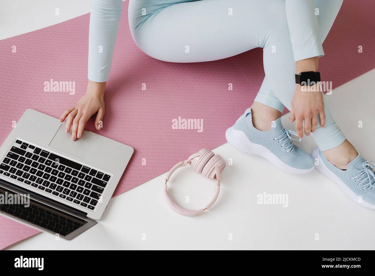Top view of unrecognizable woman sitting on mat and using laptop. Stock Photo