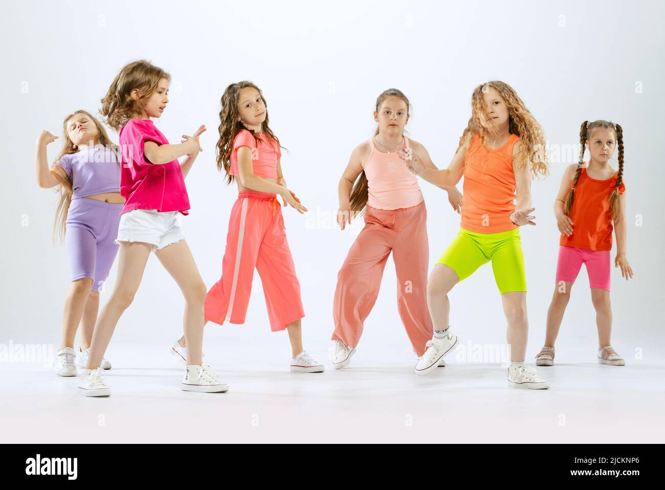Dance group of happy, active little girls in bright colorful clothes