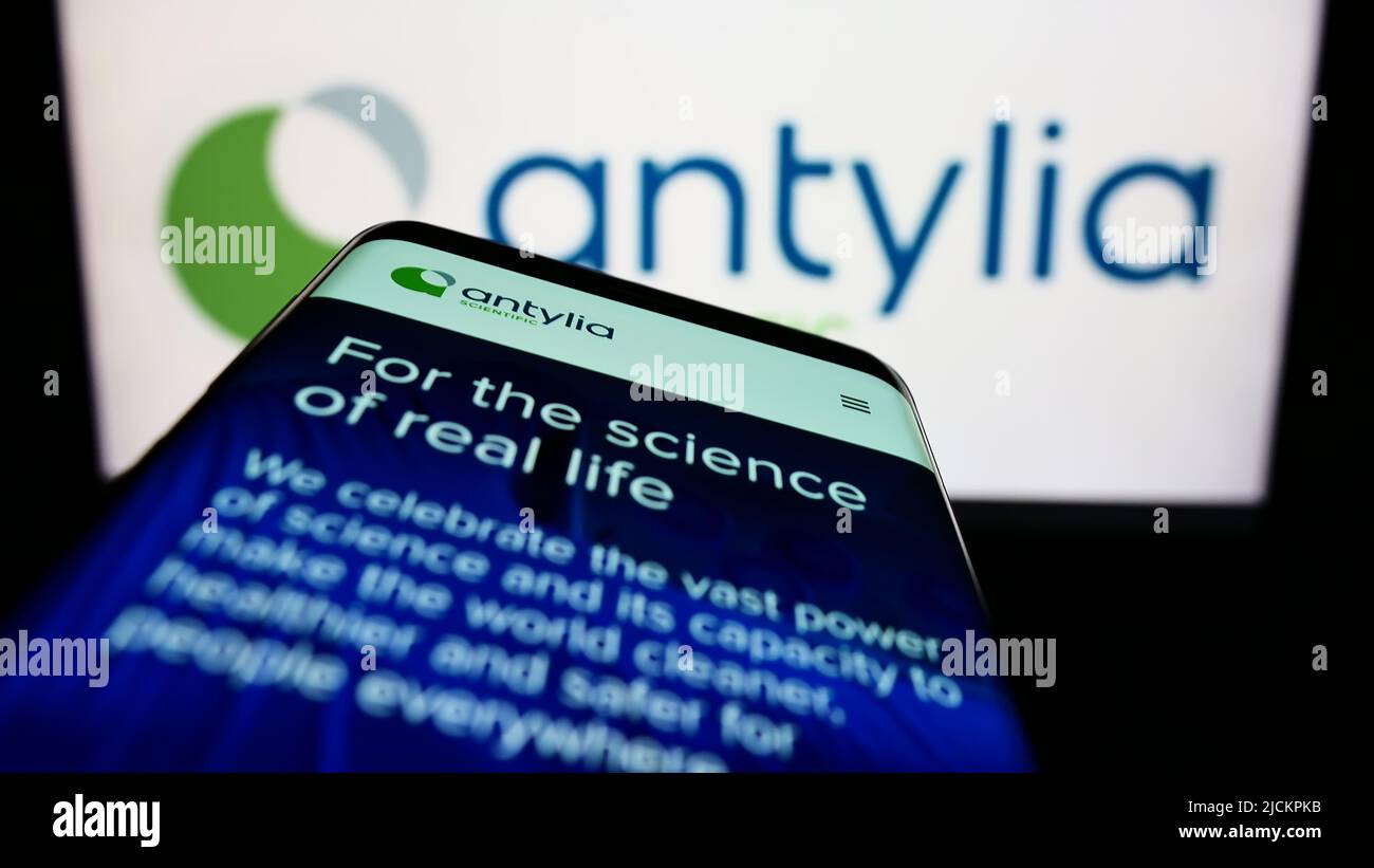 Mobile phone with website of American biotechnology company Antylia Scientific on screen in front of logo. Focus on top-left of phone display. Stock Photo