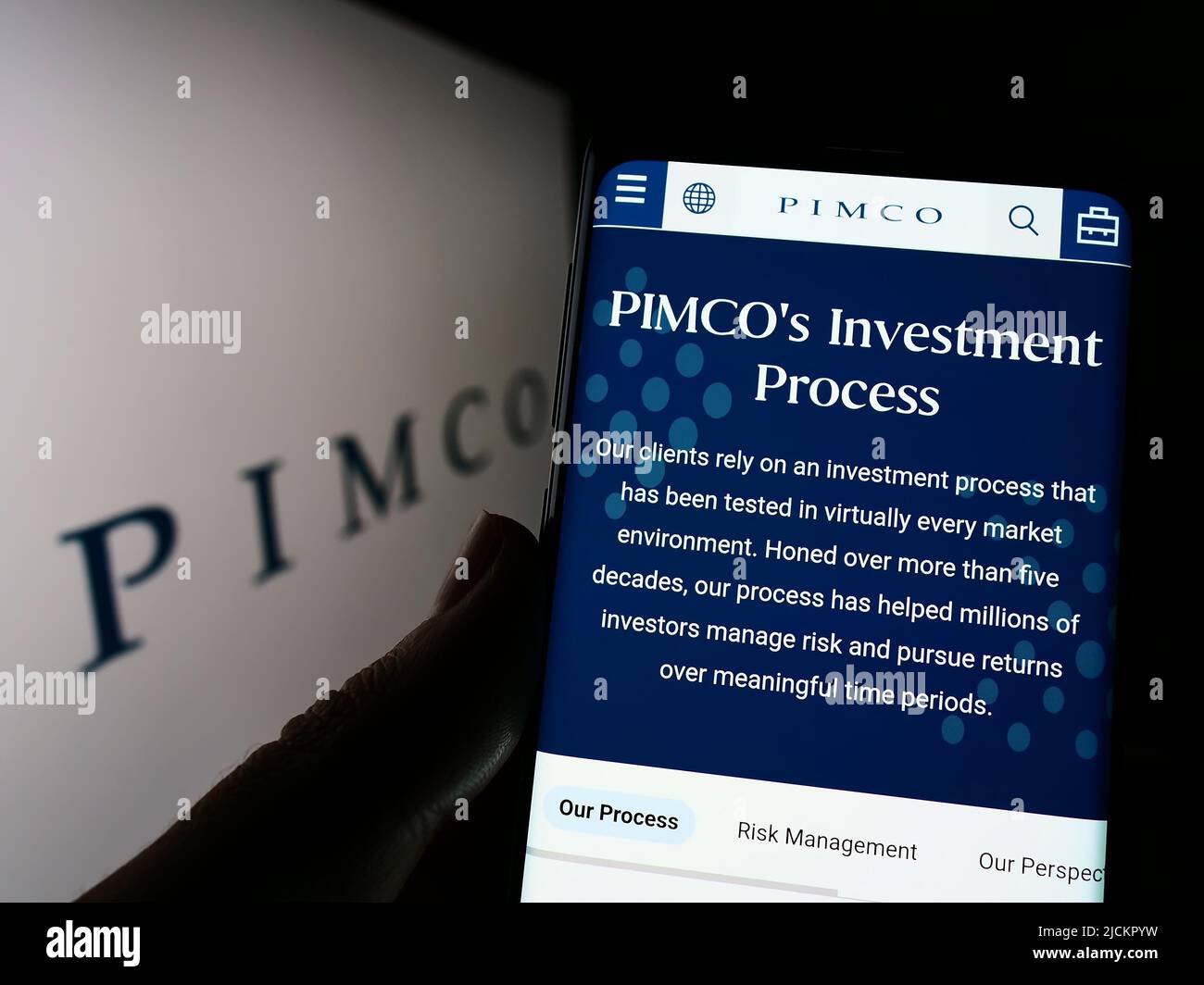 Person holding cellphone with webpage of Pacific Investment Management