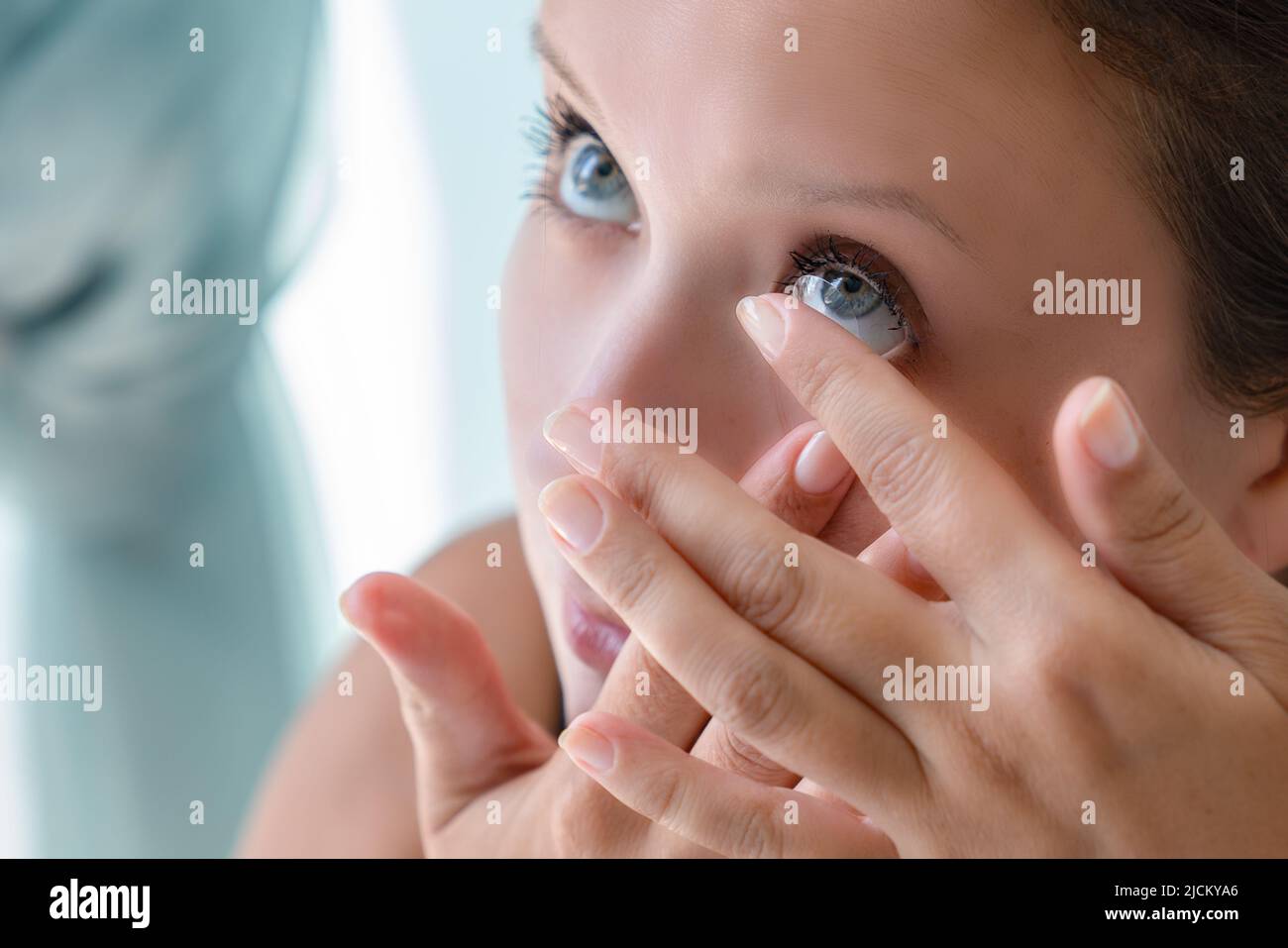 How to put contact lenses: Step by step photo instruction. Step 3: girl pulled back her lower eyelid and brought contact lens to her eye to put. Stock Photo