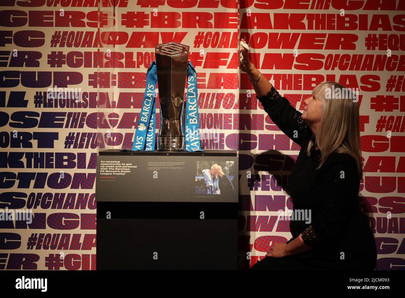 Brighton, UK. 14th June, 2022. Head of Exhibitions Helen Grundy polishes the cabinet containing the Barclays FA Women's Super League Trophy which forms part of the Goal Power Women's football Exhibition at the Brighton Museum & Art Gallery. Credit: James Boardman/Alamy Live News Stock Photo