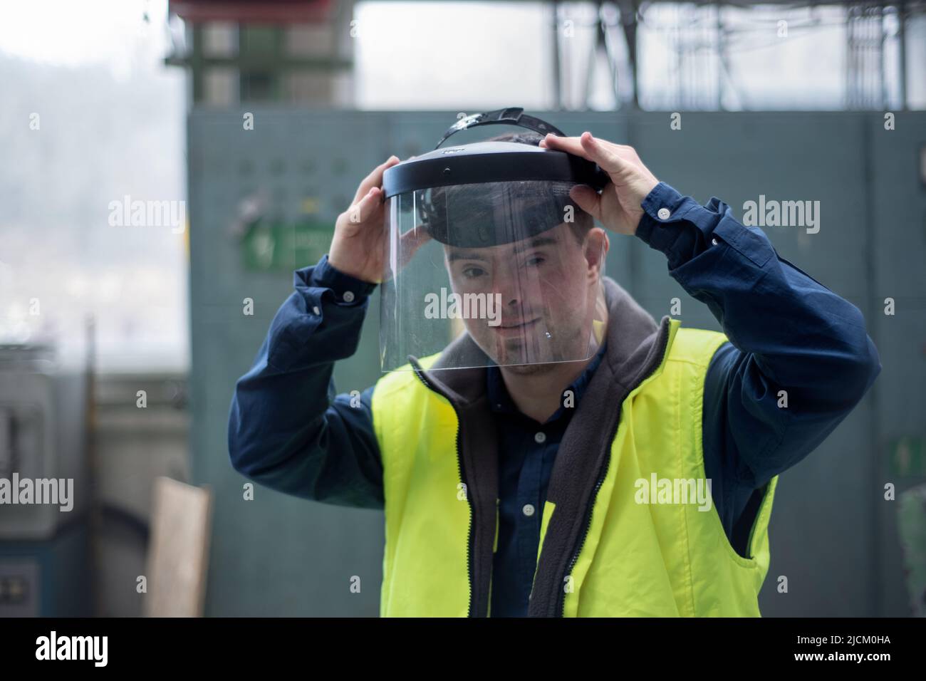 Young man welder with Down syndrome working in industrial factory, social integration concept. Stock Photo