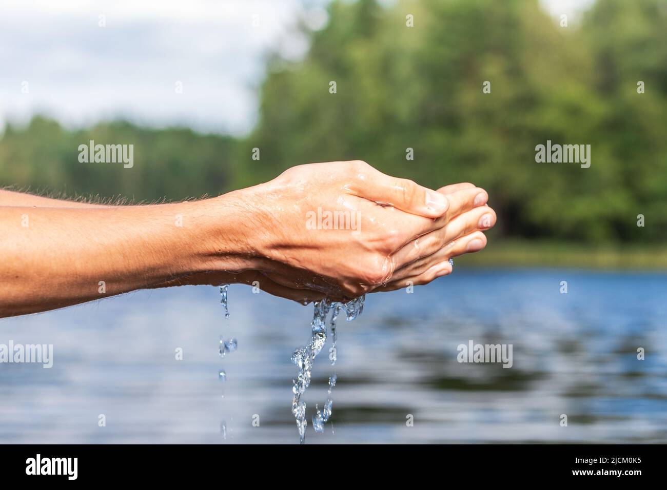 Person scoops up raw water from a lake. Natural water resources environmental awareness concept Stock Photo