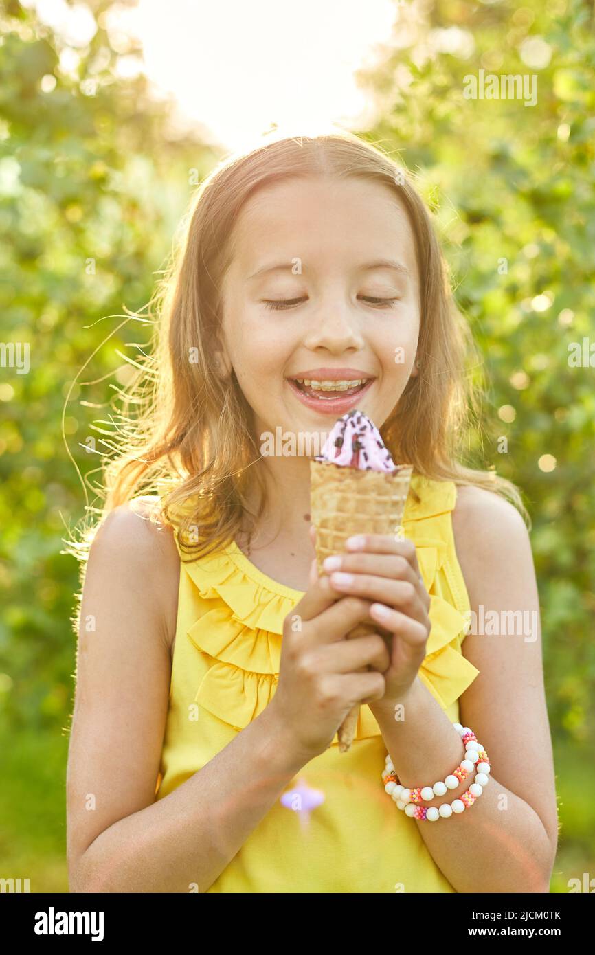Happy girl with braces eating italian ice cream cone smiling while