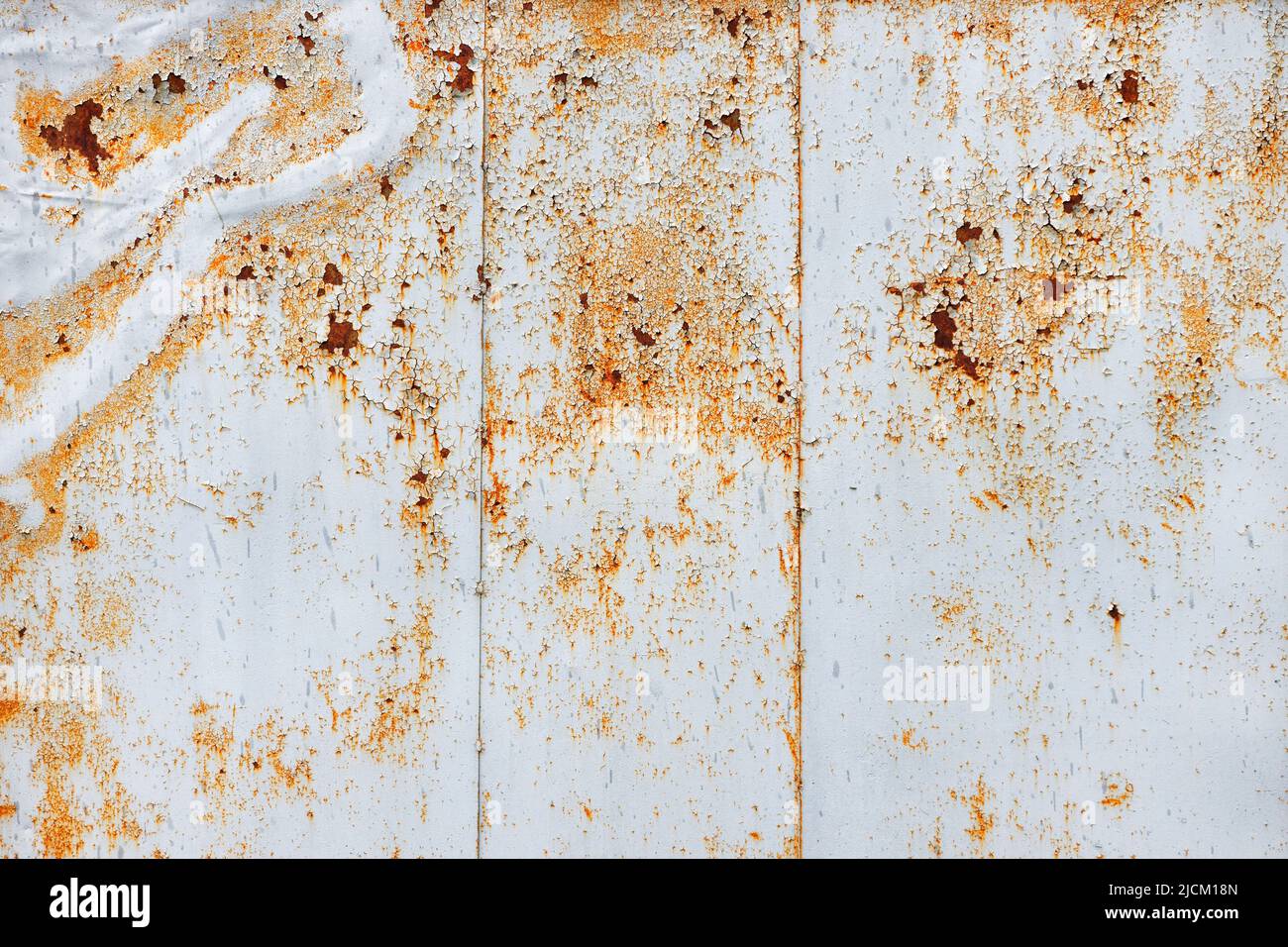 The texture of a metal sheet covered with old gray peeling paint with patches of rust and scratches. Stock Photo