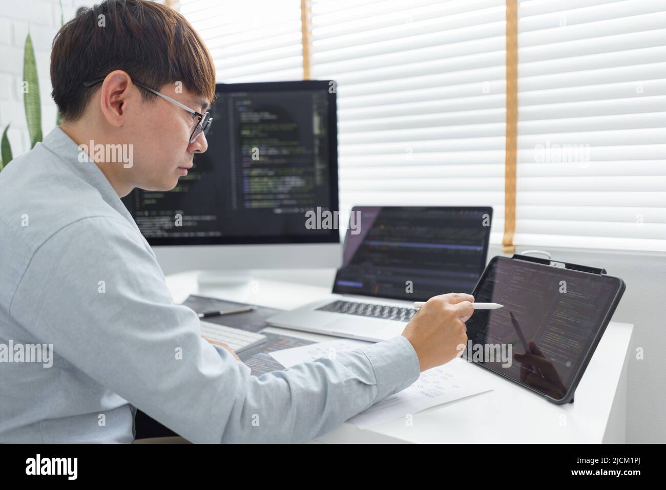 Software development concept, Male programmer point data on tablet to checking website programming. Stock Photo