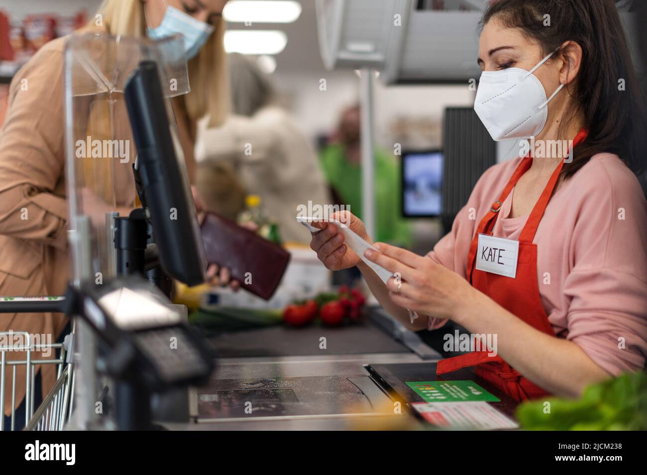 Checkout counter cashier looking to pay slip after coustomer's complaint in supermarket, Stock Photo