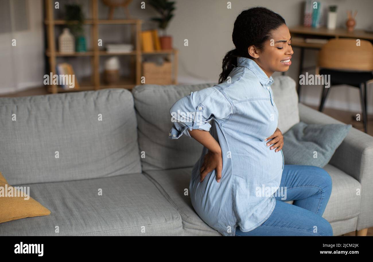 Pregnant Black Lady Having Lower Back Pain Sitting At Home Stock Photo