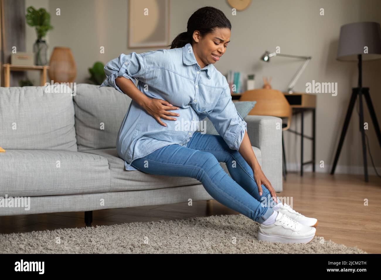 Pregnant Black Lady Lacing Shoes Touching Belly Having Spasm Indoor Stock Photo