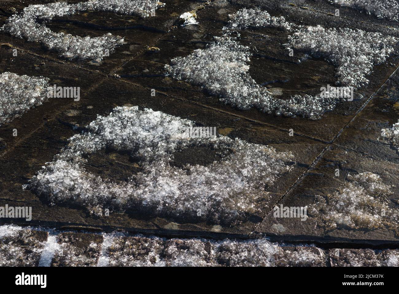 Thermal differences of heat in boundary of patio slabs become evident as fresh snow fall melts on the perimeter, or concentration of chemicals Stock Photo