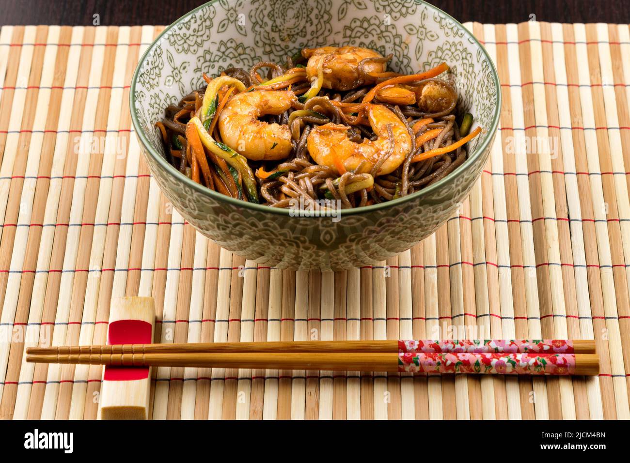 From above of appetizing traditional Japanese yakisoba dish with fried shrimps and vegetables served on bamboo mat with chopsticks in restaurant Stock Photo