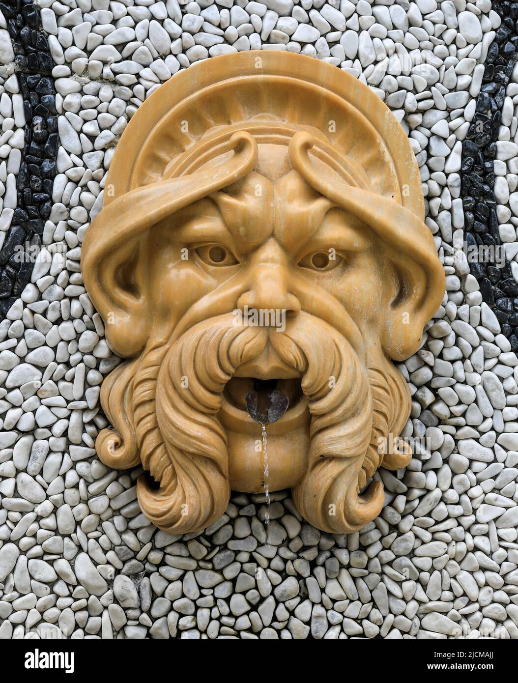 Water coming out of the mouth of a gargoyle bearded face water spout Stock Photo