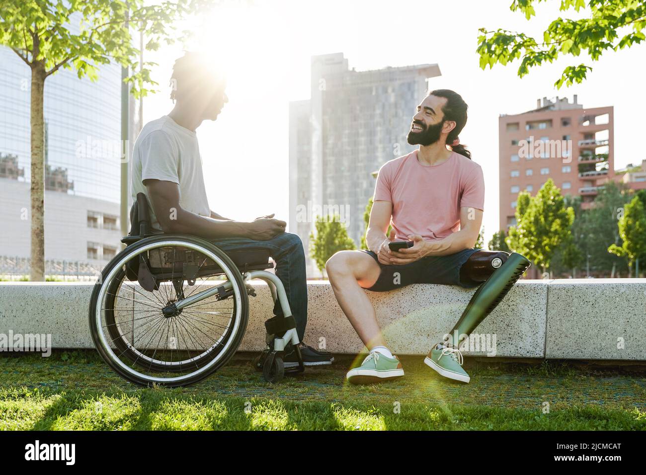 Multiethnic friends with disability having fun talking outdoor - Focus on right man with leg prosthesis Stock Photo