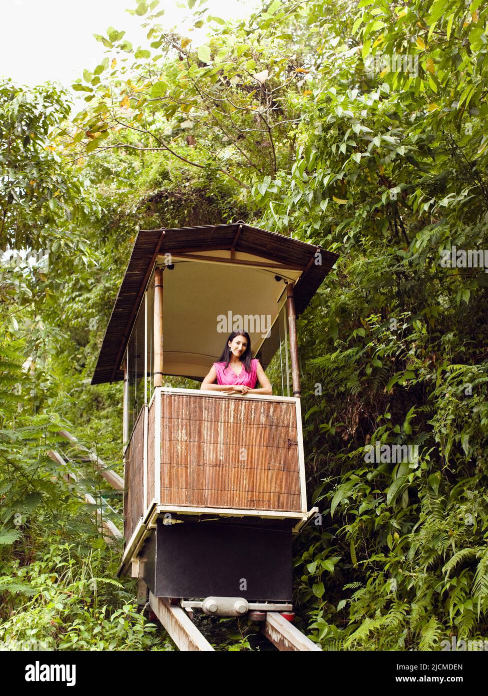 Young woman rides the funicular (or tram) at Ubud Hanging Gardens, Bali, Indonesia. The funicular runs from the main lobby to Diatas Pohon Café. Stock Photo