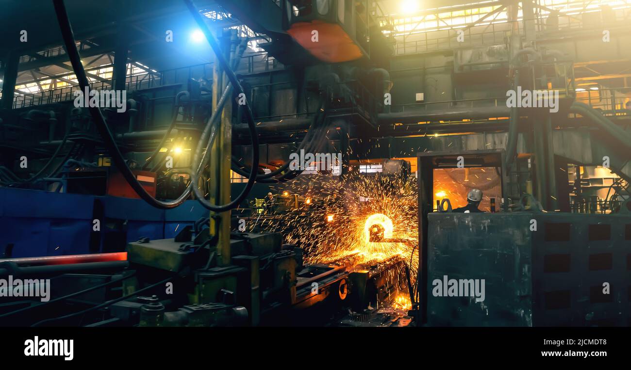 Production process of cast iron water pipes at industrial steel mill. Metallurgical foundry factory with press forming machines for manufacturing tubing. Heavy industry interior background. Stock Photo