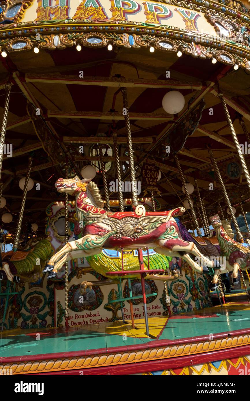 Traditional fairground circular horses merry-go-round in bright colours in the sunshine of the Royal Cornwall Show. Still an all ages attraction Stock Photo