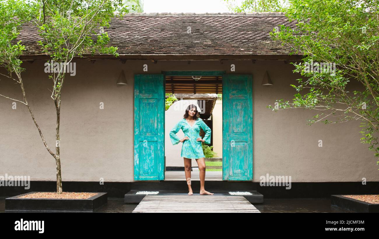A young woman stands at the entrance of a resort spa. Aturuwella, Bentota, Sri Lanka. Stock Photo