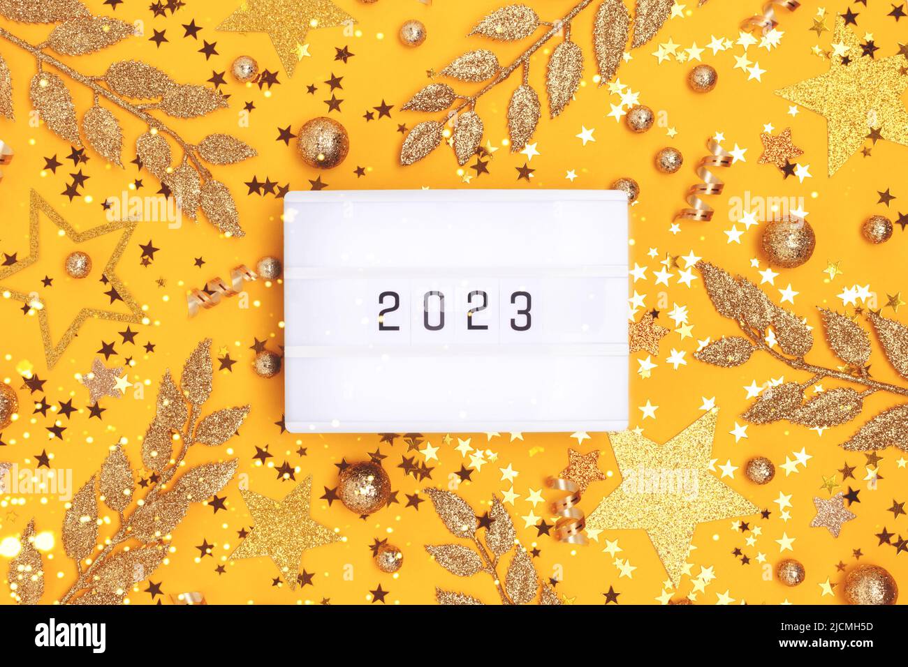 New 2023 Year. Lightbox and golden glittering decorations on a yellow background. Stock Photo
