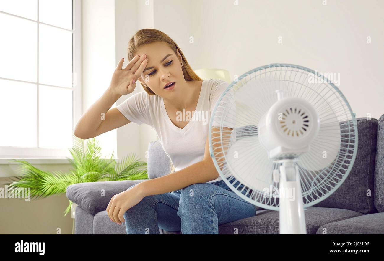 Woman tired of summer heat sitting at home and trying to get some fresh