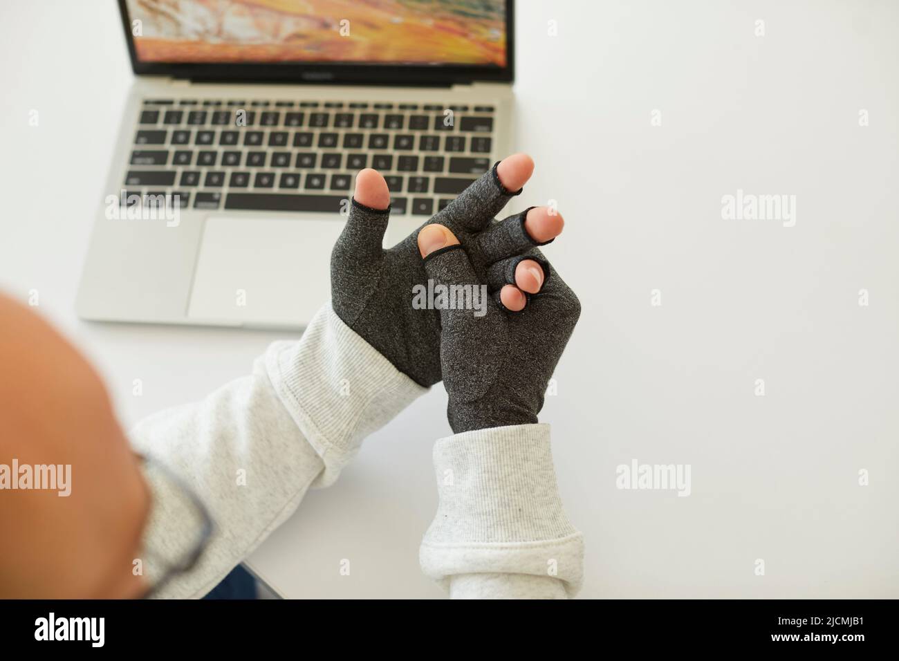 Man who has rheumatoid arthritis wears compression gloves for relieving pain in his hands Stock Photo