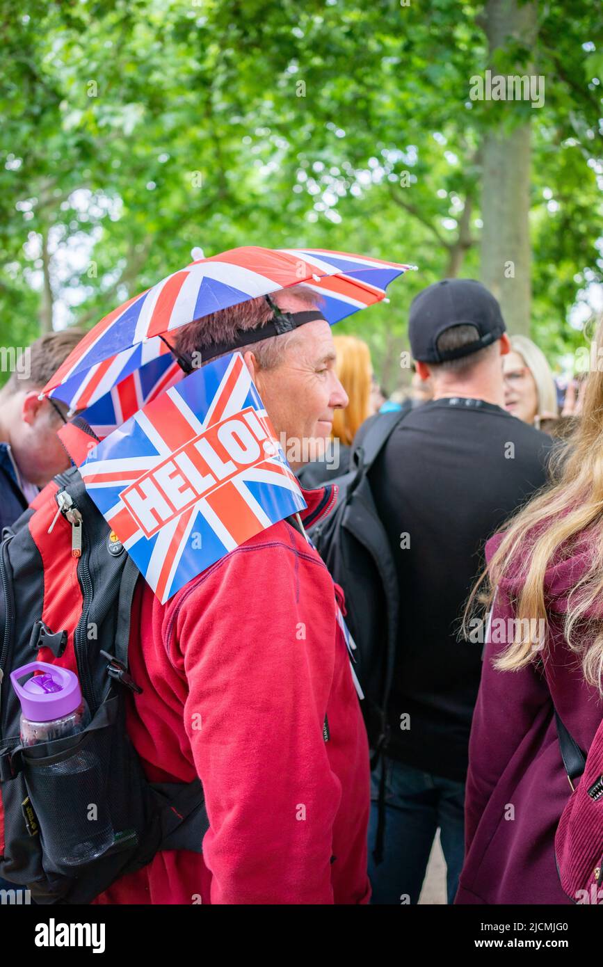 Man wearing umbrella hat on The Mall in London, England watching The Platinum Jubilee procession of Queen Elizabeth II being celebrated in 2022 Stock Photo