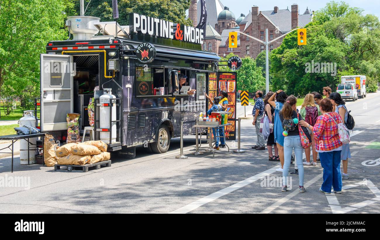 A group of people lining up in a food truck selling Poutine and More. The scene is part of the Word On The Street Festival. Stock Photo