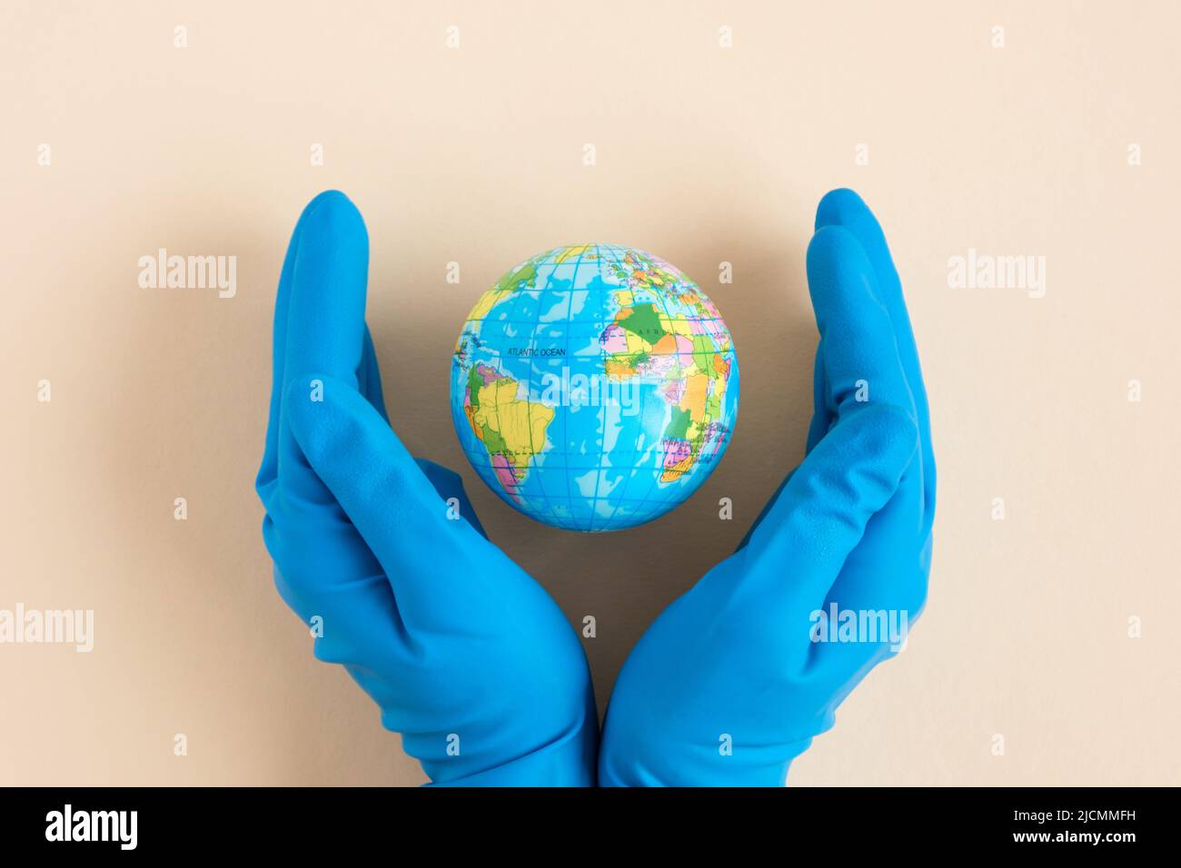 Earth globe in hands in blue protective glove on a clean. The concept of protecting nature, ecology and global peace. COVID-19 pandemic Stock Photo