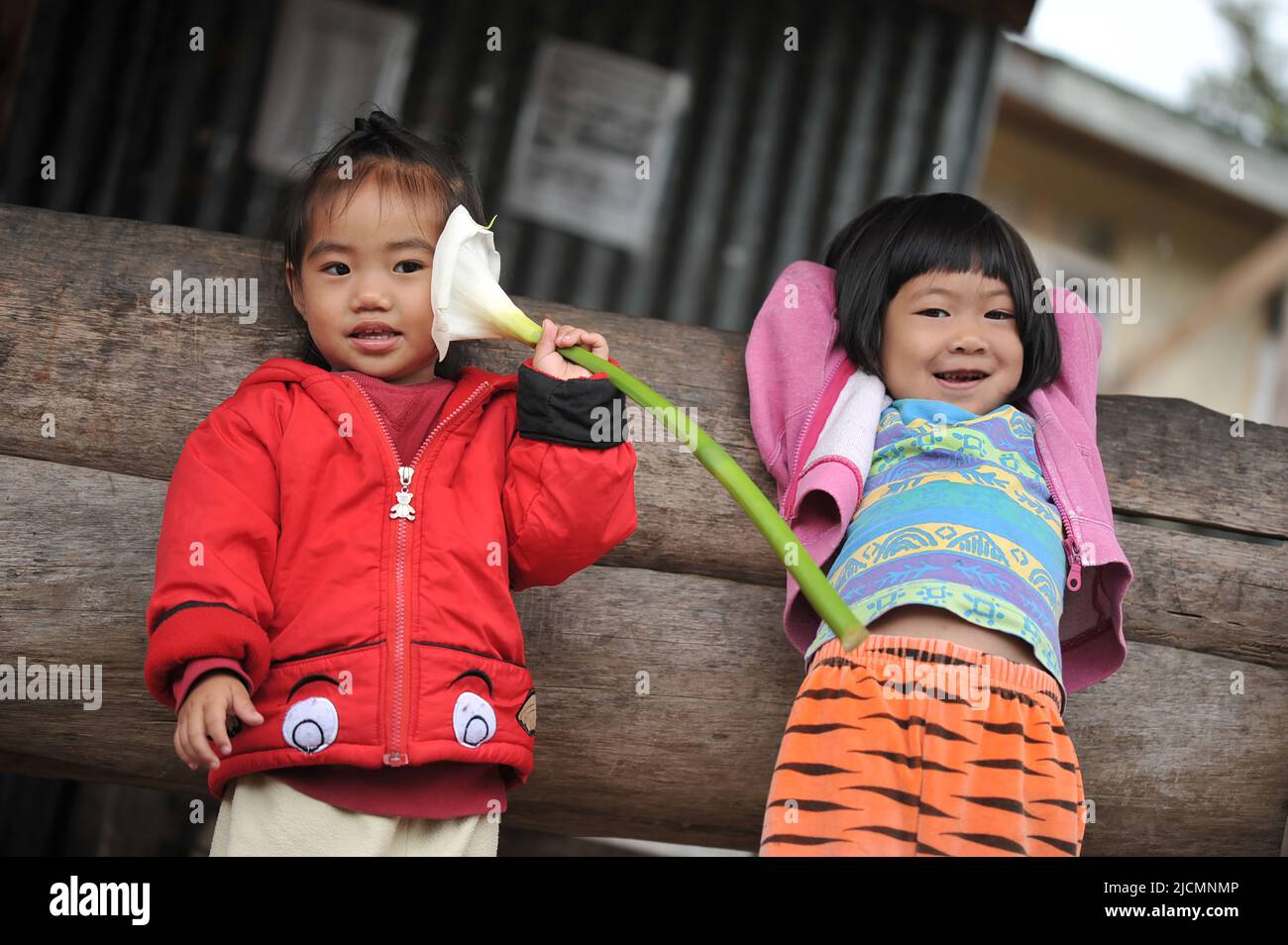 Mountain Province, Philippines: two locals, young girls wearing colorful clothes, engaging with tourists passing by their neighborhood in Sagada. Stock Photo