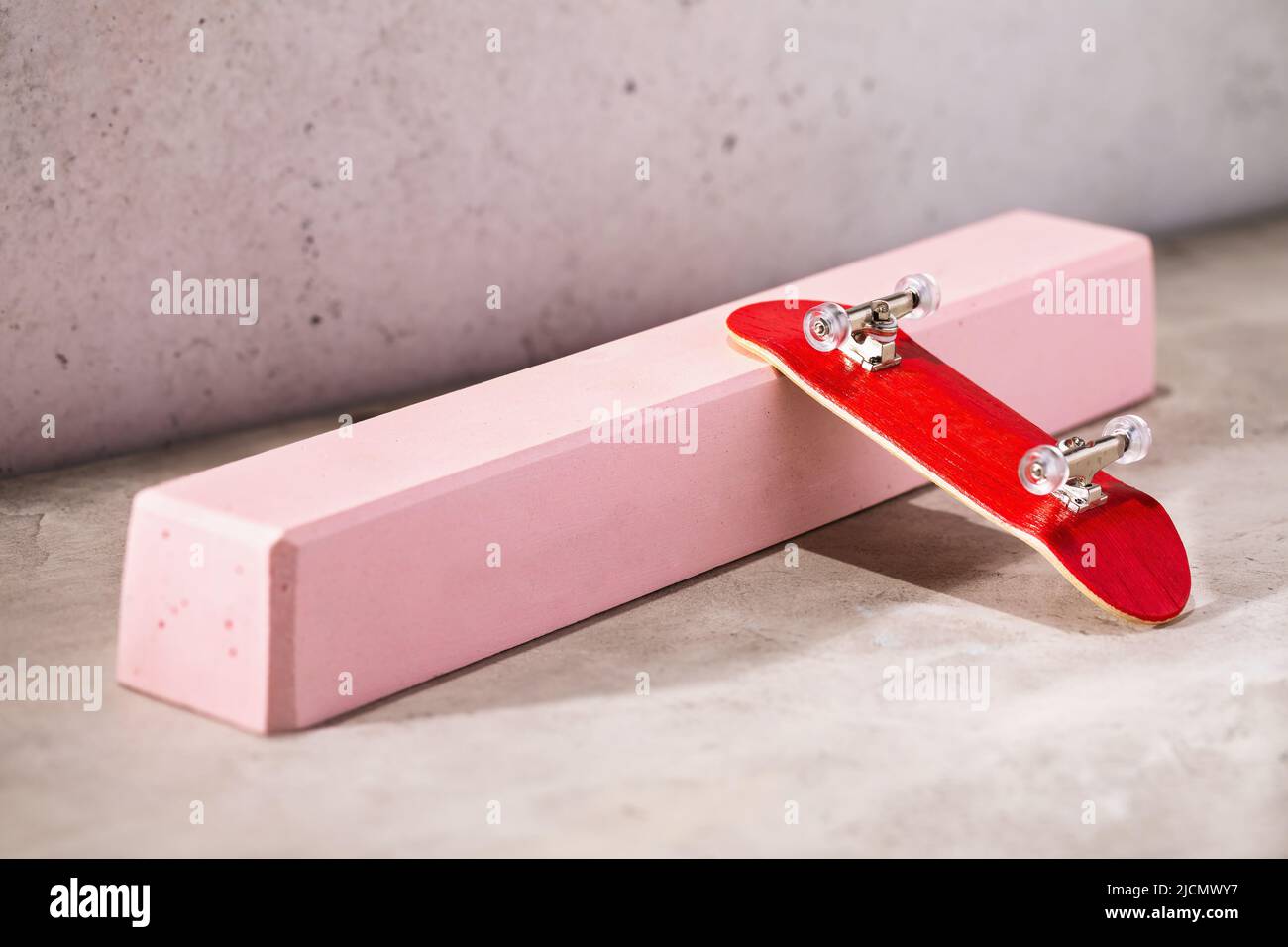 Red fingerboard on a pink gypsum railing on an abstract background Stock Photo