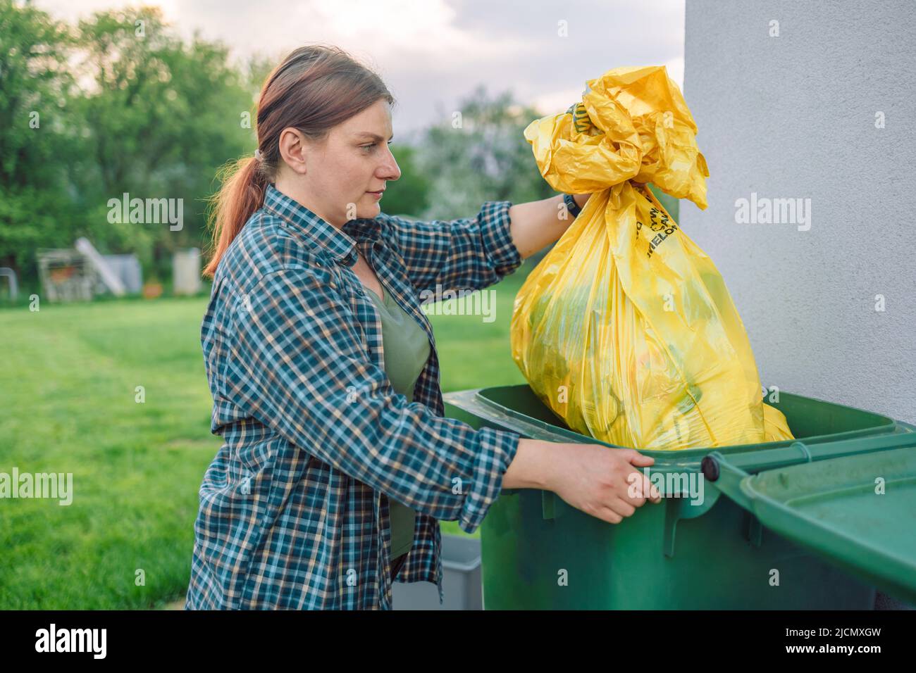 European 30s woman throwing garbage into the recycling bin in the