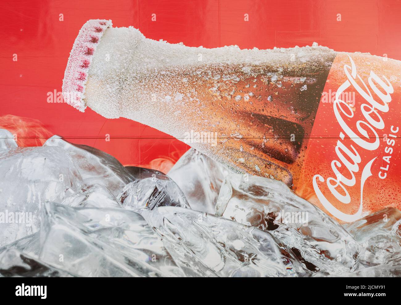 Minsk, Belarus, June 2022 - Classic Coca-Cola bottle with ice on red background. Stock Photo