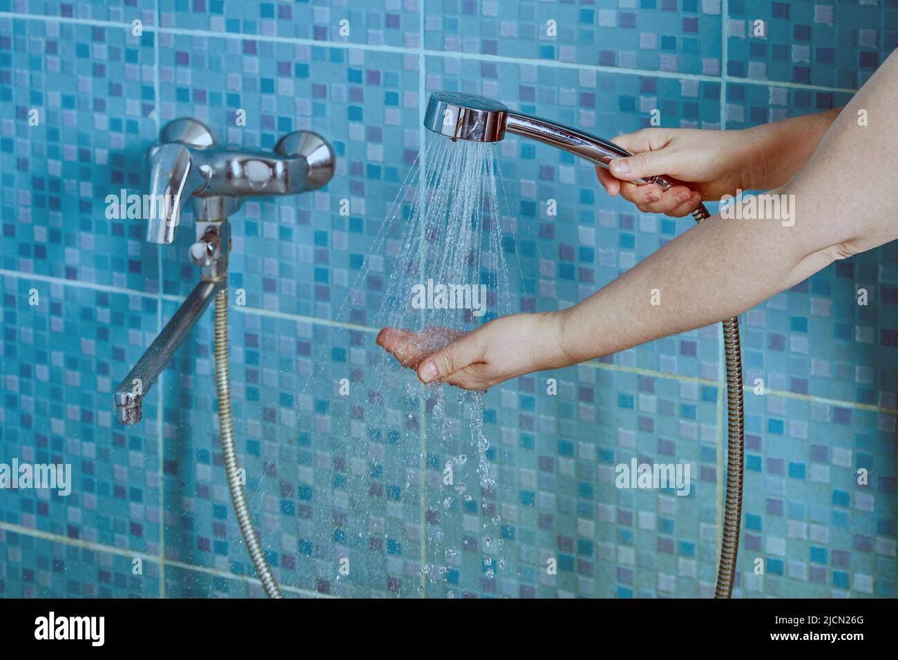 Flow of water from shower head is directing to palm, to control