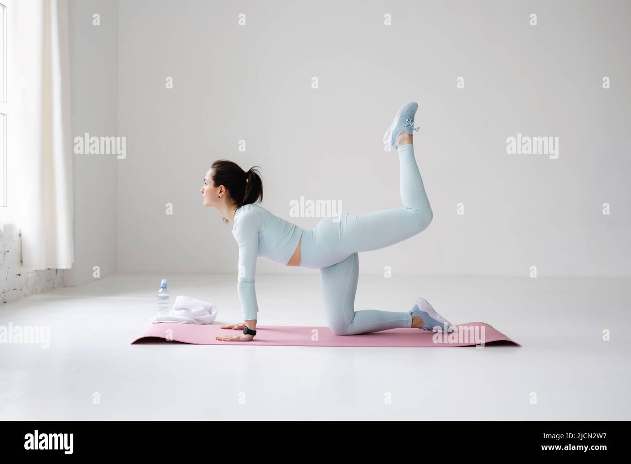 Young fit woman doing leg exercises on fitness mat indoors. Stock Photo