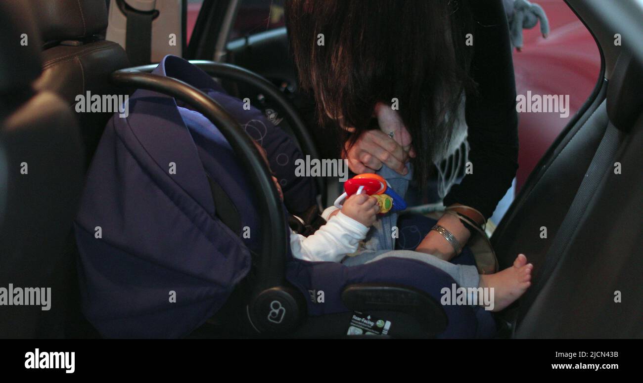 Mother securing her baby in the car seat of car Stock Photo - Alamy