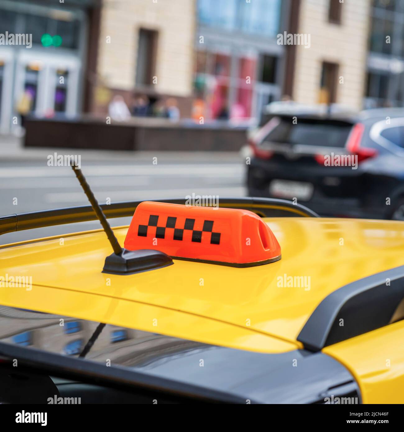 Yellow taxi car roof sign close-up, blurred abstract city street background, selective focus Stock Photo